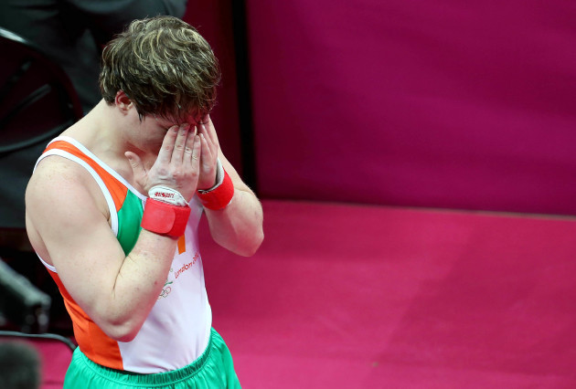Kieran Behan holds his head after the floor exercise