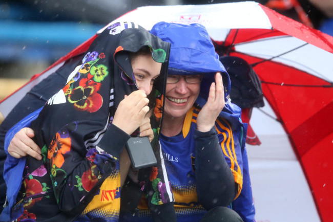 Supporters take shelter from a heavy shower