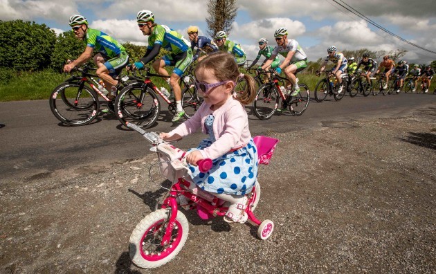 3 year old Anna Crombie rides her bike as the An Post Rás passes through Rahugh