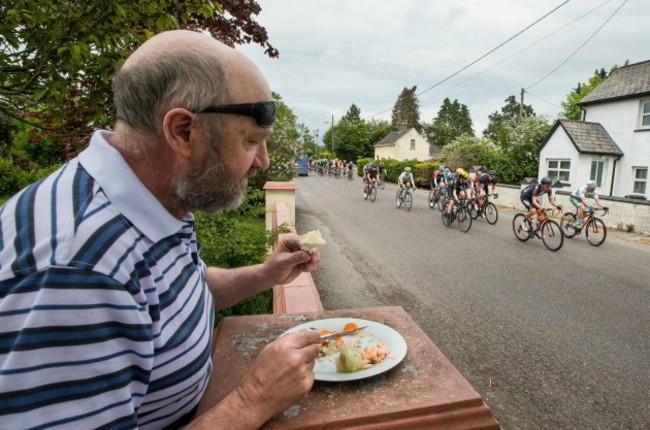 Billy Finnegan eats his dinner on his front wall as the riders of An Post R&aacute;s pass through Rathcormac