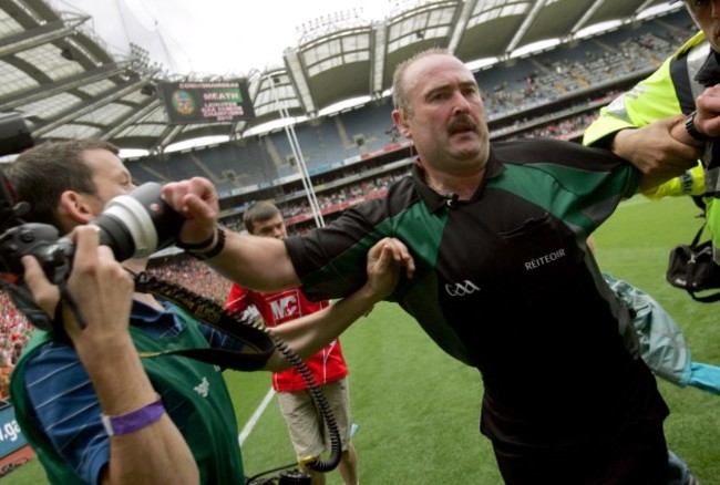 Referee Martin Sludden is escorted from the pitch