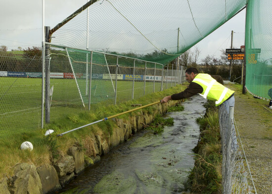 A steward at Clonakilty GAA attempts to retrieve the ball over a stream during the teams warm up