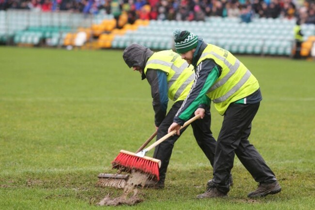 Ground staff removing excess water from the pitch prior to throw in