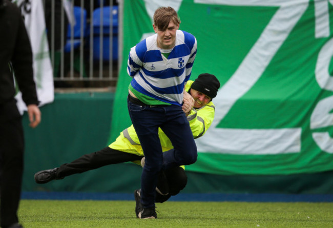 A steward falls while attempting to tackle a pitch invader