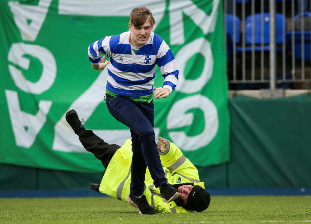 A steward falls while attempting to tackle a pitch invader