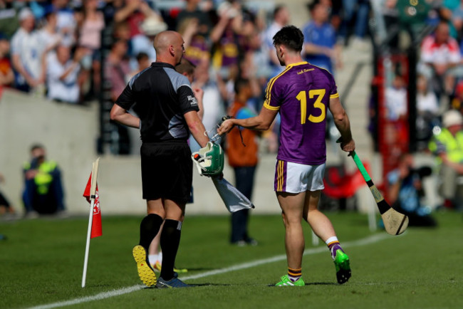 Harry Kehoe shows his broken helmet to assistant referee John Keenan