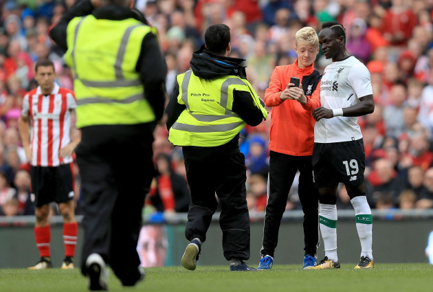 A supporter attempt's to get a selfie with Liverpool's Sadio Mané as security run on to the pitch