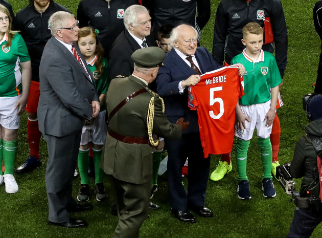 President Michael D Higgins holds up a jersey presented by Wales in tribute to Ryan McBride