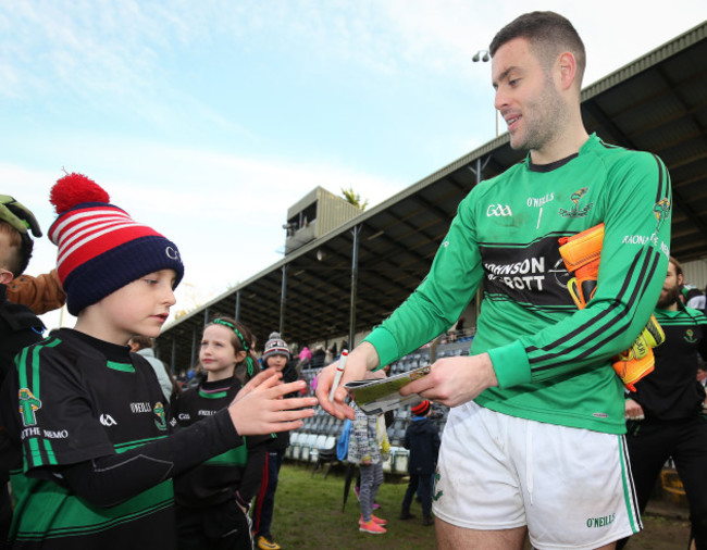 Micheal Aodh Martin signs a programme for a young fan after the game