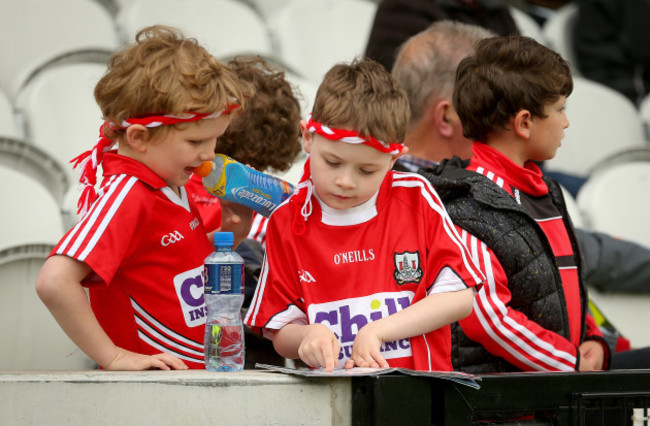 Young Cork fans read the programme before the game
