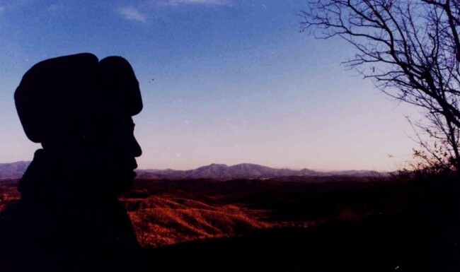 A KPA officer stares over the DMZ into South Korea