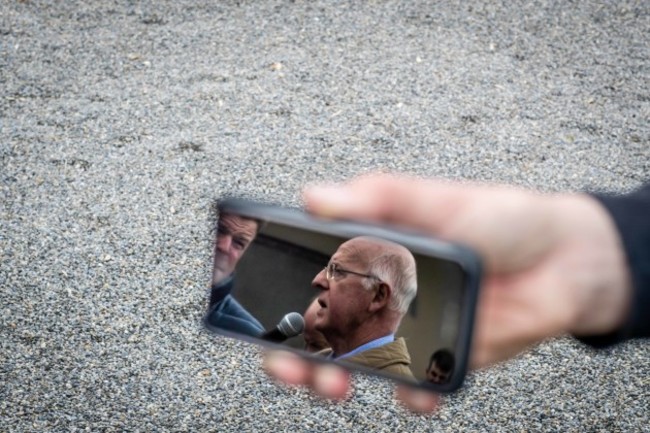 John Oxx being interviewed by Kevin O'Ryan as seen in a reflection on a reporters' phone