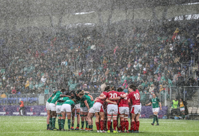 a-view-of-the-ireland-and-wales-teams-in-a-huddle-during-the-tough-weather-conditions