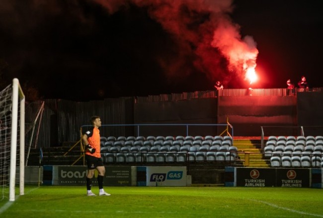 brian-murphy-watches-on-as-drogheda-fans-outside-the-fence-let-off-a-flare-to-celebrate-their-goal