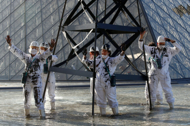 greenpeace-activists-stand-next-to-an-oil-drilling-rig-replica-in-front-of-the-glass-pyramid-of-the-louvre-museum-during-a-protest-in-paris-as-part-of-the-launching-of-an-european-citizens-initiative