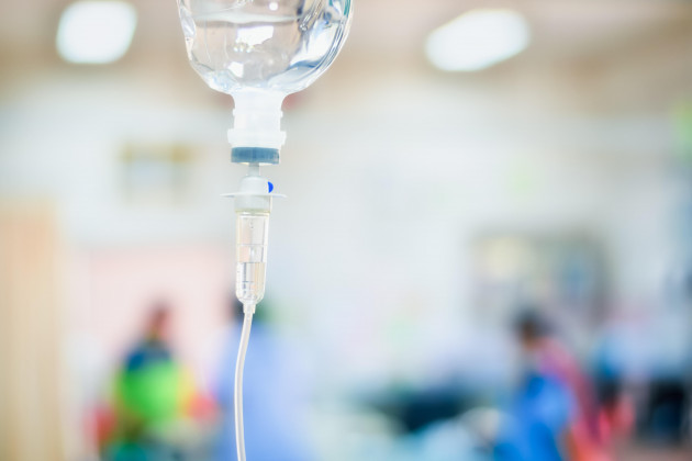 close-up-saline-iv-drip-for-patient-in-hospital-with-copy-space-on-n-blurred-doctor-give-medical-and-other-attention-to-a-sick-person