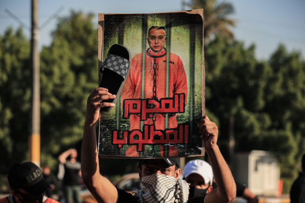 baghdad-iraq-06th-nov-2021-a-man-holds-up-a-poster-of-iraqi-prime-minister-mustafa-al-kadhimi-reading-wanted-criminal-during-a-mourning-event-in-front-of-one-of-the-gates-of-baghdads-green-zon