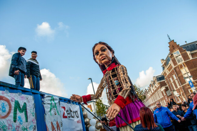 two-children-are-seen-standing-up-of-a-ship-container-to-see-the-giant-puppet-closer-amare-a-new-cultural-hub-in-the-center-of-the-hague-has-organized-as-a-part-of-its-open-festival-the-visit-of-t