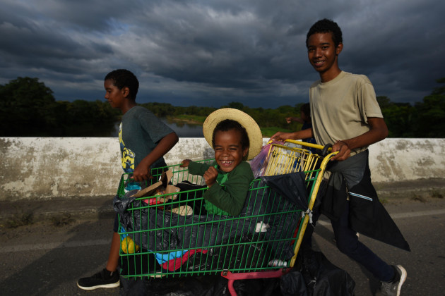 veracruz-mexico-16th-nov-2021-migrant-children-laugh-and-get-ahead-with-the-help-of-a-shopping-cart-with-numerous-migrants-walking-towards-the-us-border-to-dpa-thousands-of-migrants-head-north