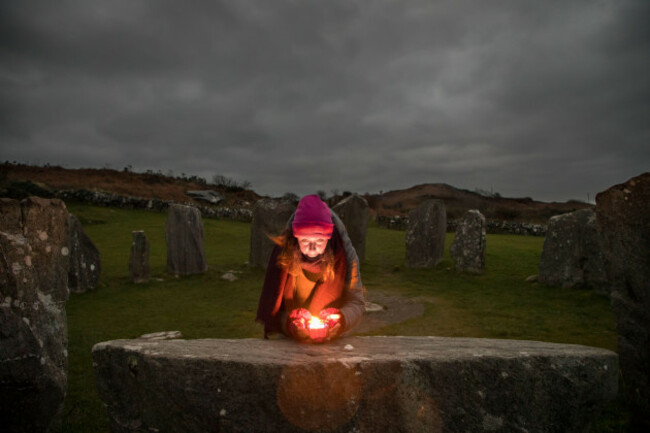 drombeg-glandore-cork-ireland-21st-december-2021-shaman-and-healer-amy-russell-from-rosscarbery-lighting-a-candle-on-the-altar-stone-while-waiting-to-observe-the-sunrise-during-the-winter-solstic