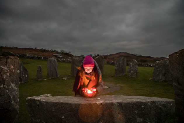 drombeg-glandore-cork-ireland-21st-december-2021-shaman-and-healer-amy-russell-from-rosscarbery-lighting-a-candle-on-the-altar-stone-while-waiting-to-observe-the-sunrise-during-the-winter-solstic
