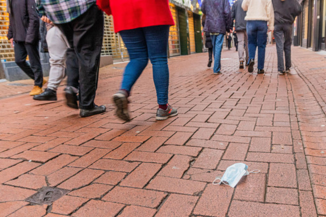 amsterdam-netherlands-19-dec-2021-abandoned-mouth-cap-and-feet-and-legs-of-people-strolling-through-the-locked-down-kalverstraat-usually-one-of-the-most-busy-shopping-streets-of-amsterdam-as-from
