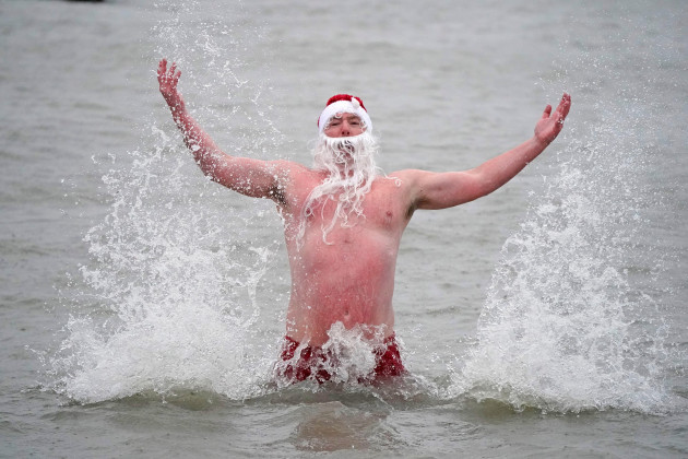 patrick-corkery-wears-a-santa-hat-and-beard-as-waves-crash-over-him-during-a-christmas-day-dip-at-sandy-cover-near-dublin-picture-date-saturday-december-25-2021