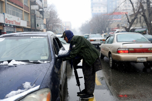 a-taliban-fighter-searches-a-car-as-he-stands-guard-at-a-checkpoint-during-a-snowfall-in-kabul-afghanistan-january-3-2022-reutersali-khara