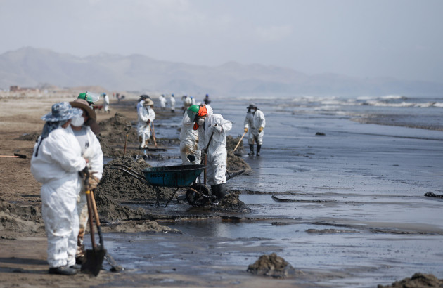 workers-clean-up-an-oil-spill-caused-by-abnormal-waves-triggered-by-a-massive-underwater-volcanic-eruption-half-a-world-away-in-tonga-at-the-peruvian-beach-in-ventanilla-peru-january-18-2022-reu