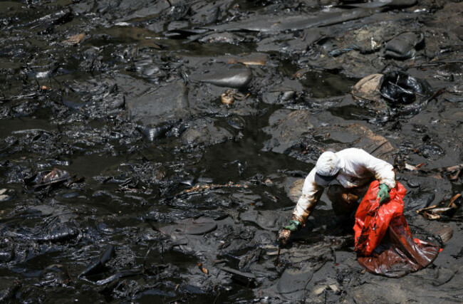 a-worker-cleans-up-an-oil-spill-caused-by-abnormal-waves-triggered-by-a-massive-underwater-volcanic-eruption-half-a-world-away-in-tonga-at-the-peruvian-beach-in-ventanilla-peru-january-18-2022-r