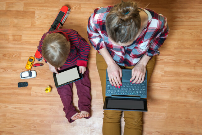 boyandmotherusingtabletandlaptopwhileplayingwith