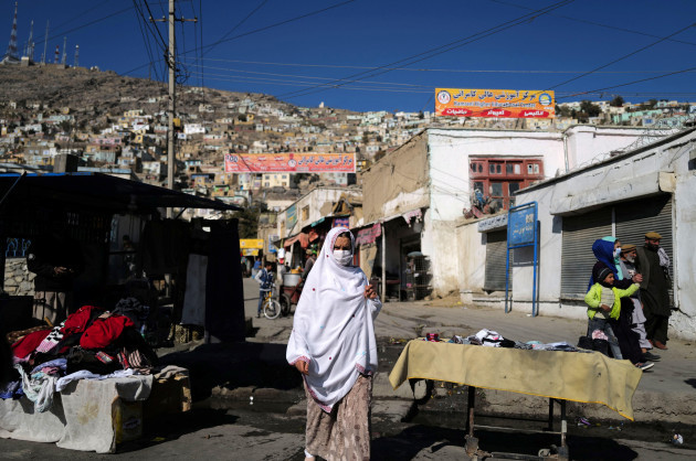 a-woman-walks-past-a-second-hand-clothes-vendor-in-kabul-afghanistan-november-5-2021-reuterszohra-bensemra