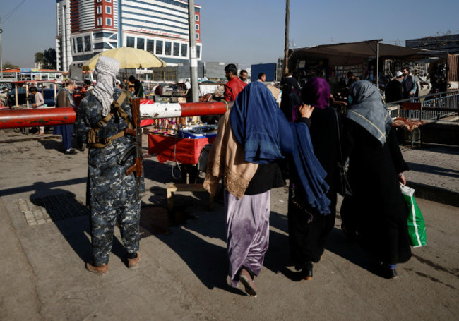 afghan-women-walk-past-a-taliban-fighter-standing-guard-at-the-market-in-kabul-afghanistan-october-24-2021-reuterszohra-bensemra