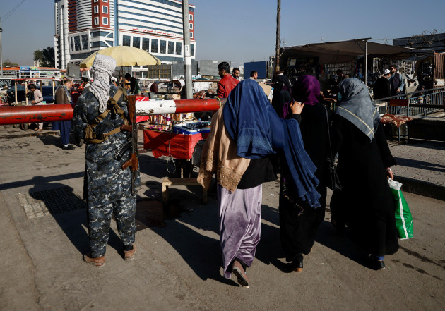 afghan-women-walk-past-a-taliban-fighter-standing-guard-at-the-market-in-kabul-afghanistan-october-24-2021-reuterszohra-bensemra
