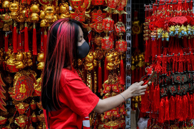 manila-philippines-1st-feb-2022-a-woman-wearing-a-protective-mask-as-precaution-against-the-coronavirus-disease-shops-for-lucky-charms-in-celebration-of-the-lunar-new-year-near-the-seng-guan-templ