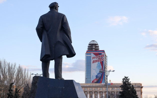 donetsk-ukraine-21st-feb-2022-a-view-of-a-monument-to-russian-revolutionary-vladimir-lenin-and-a-poster-reading-russian-donbass-denis-pushilin-head-of-the-donetsk-peoples-republic-asks-russi