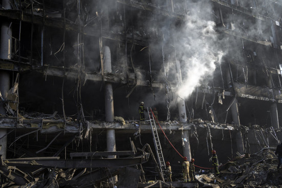 Firefighers attend the scene of the burnt out ruins of a shopping centre in Kyiv.