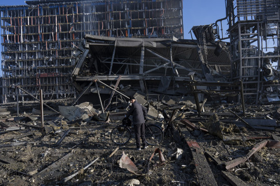 A man walks with his bicycle outside the destroyed shoppin centre in Kyiv.