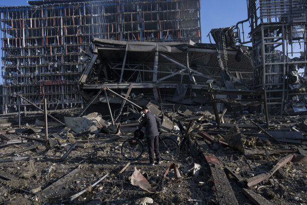 A man walks with his bicycle outside the destroyed shoppin centre in Kyiv.