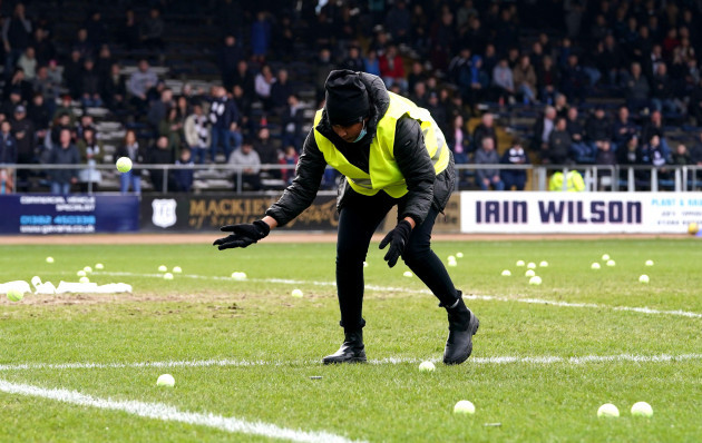 a-steward-clears-tennis-balls-off-the-pitch-during-the-cinch-premiership-match-at-the-kilmac-stadium-dundee-picture-date-sunday-march-20-2022