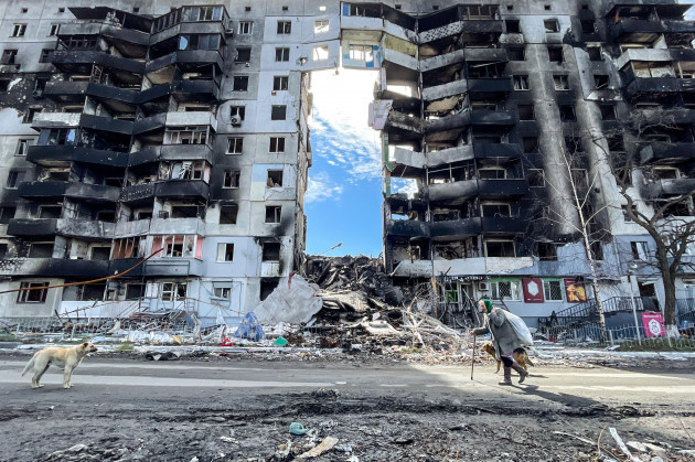 april-7-2022-borodyanka-of-bucha-raion-kyiv-oblast-ukraine-an-elderly-woman-with-her-dogs-walk-past-a-damaged-residential-buildings-by-a-russian-air-strike-in-borodyanka-bucha-raion-of-kyiv-obla