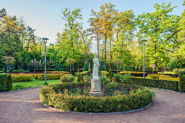 gypsum-sculpture-of-a-woman-with-a-jug-on-a-flowerbed-among-bushes-and-trees-in-a-city-park-in-bucha-ukraine