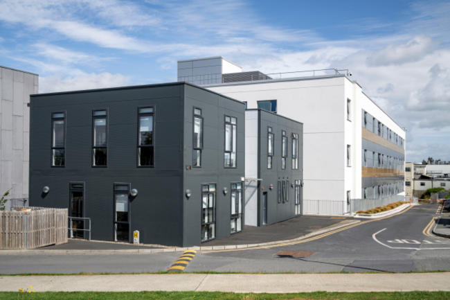 Two large rectangular buildings with numerous windows - a dark grey one in the foreground and white building in the back.