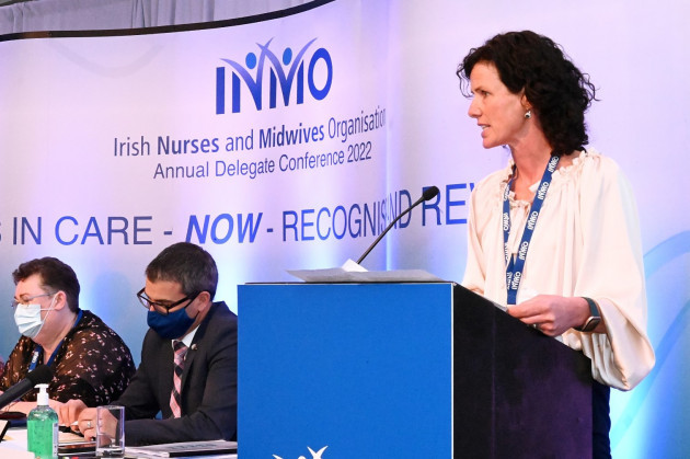 Ann Noonan wearing a white top standing at a podium speaking at an INMO event.