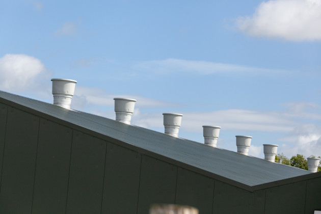 Side and roof of a grey poultry shed with air vents coming out the top of the roof
