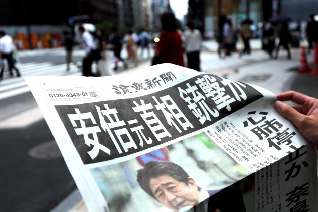 pedestrians-take-copies-of-an-extra-edition-newspaper-reporting-japans-former-prime-minister-shinzo-abe-was-shot-during-an-election-campaign-event-in-the-city-of-nara-western-japan-in-tokyo-on-july