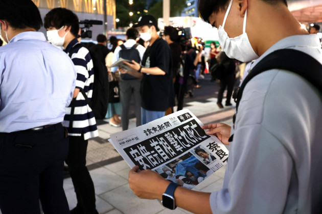 tokyo-japan-8th-july-2022-a-man-reads-an-extra-edition-news-paper-which-reports-former-prime-minister-shinzo-abe-was-shot-dead-during-an-election-campaign-in-nara-prefecture-western-japan-by-a-gu