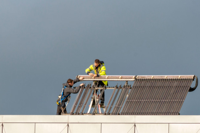 technicians-maintain-photo-voltaic-solar-panels-on-office-building-roof-in-killarney-ireland-as-climate-change-concept