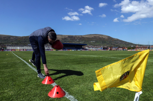 a-memeber-of-the-antrim-coaching-team-lays-out-cones-at-corrigan-park-for-the-warmup