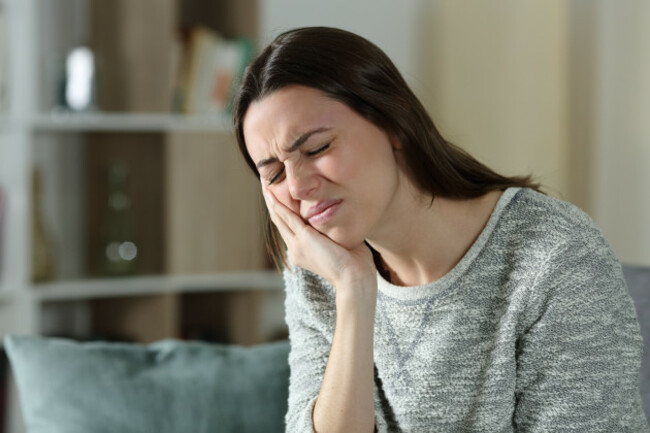 stressedwomancomplainingsufferingtoothachesittingonacouchat